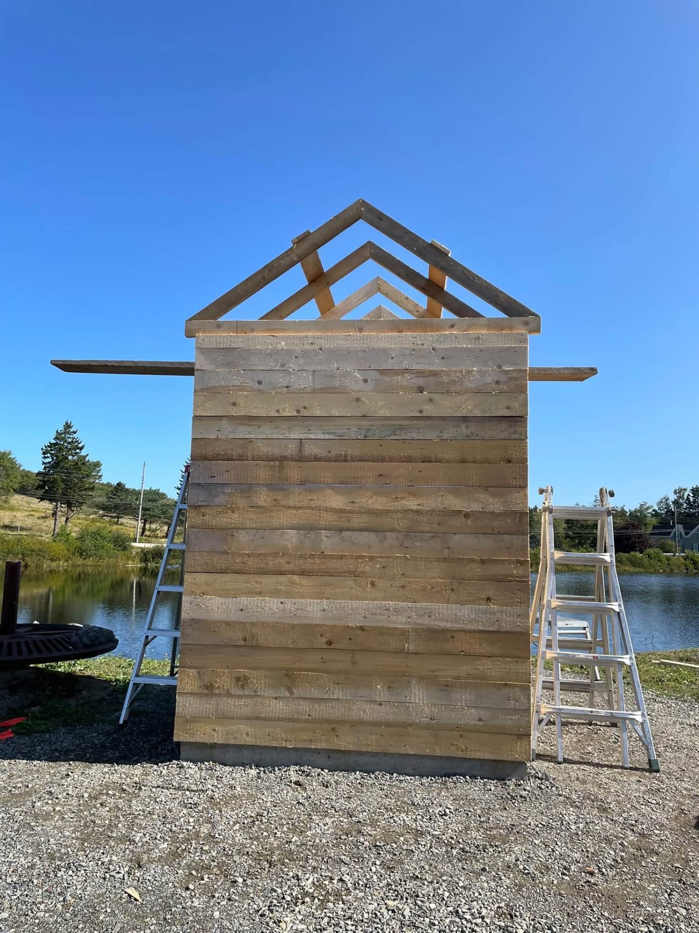 Timber siding and roof framing in progress beside the water