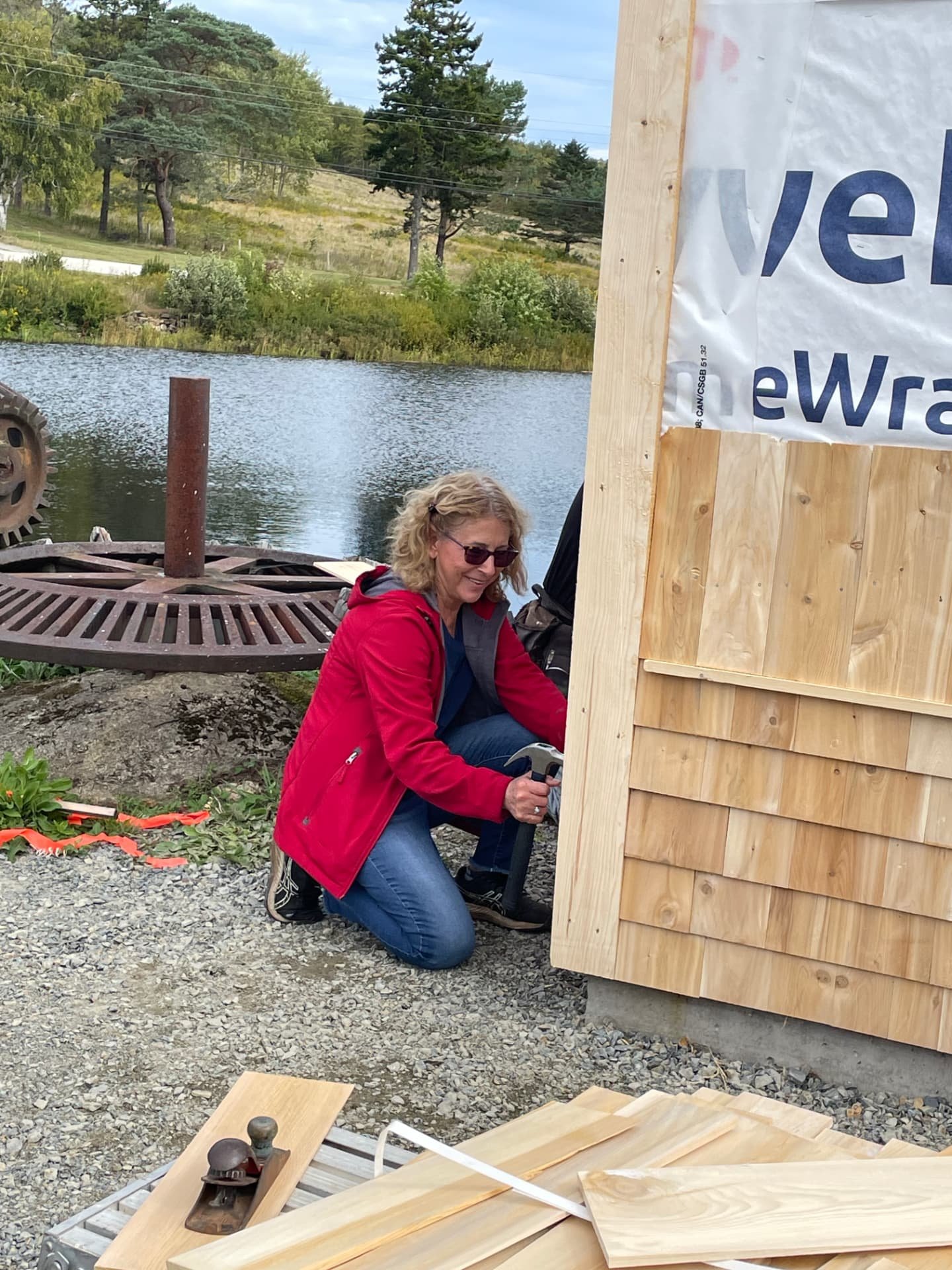 A volunteer adding cedar siding to the Clare Wind Phone