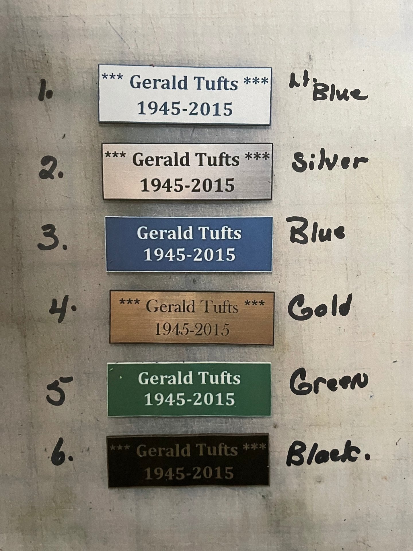 Sample memory badges in light blue, silver, blue, gold, green, and black, each engraved with a name and dates.